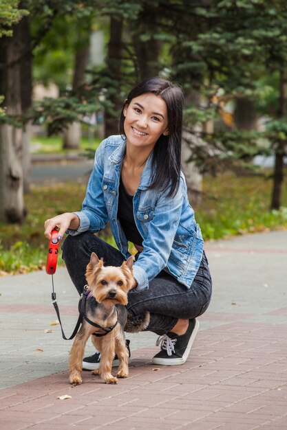 Bella ragazza asiatica per una passeggiata nel parco in estate con il suo cane Yorkshire Terrier