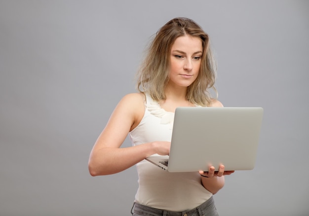 Bella ragazza astuta che per mezzo del computer portatile