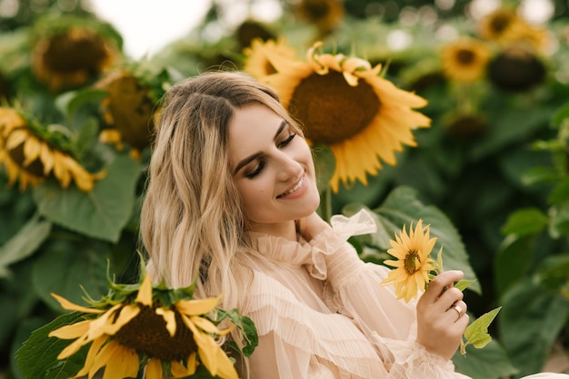 Bella ragazza attraente in un campo di girasoli