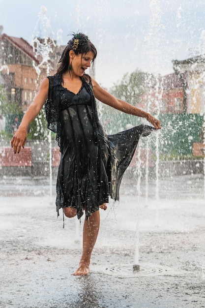 Bella ragazza balla in una fontana