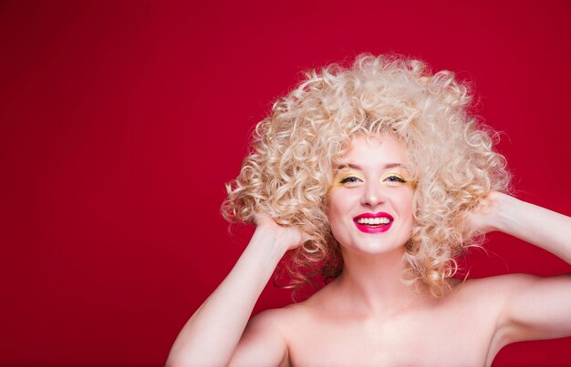 Bella ragazza bionda alla moda in stile retrò con voluminosa acconciatura riccia