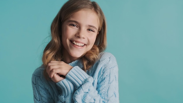 Bella ragazza bionda carina vestita con un maglione accogliente che sembra affascinante in posa sulla fotocamera su sfondo blu Espressione del viso