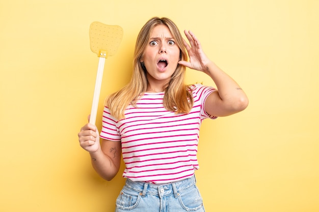 Bella ragazza bionda che grida con le mani in aria. uccidere mosche concetto