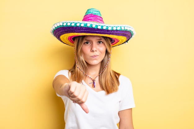 Bella ragazza bionda che si sente arrabbiata, mostrando i pollici verso il basso. concetto di cappello messicano