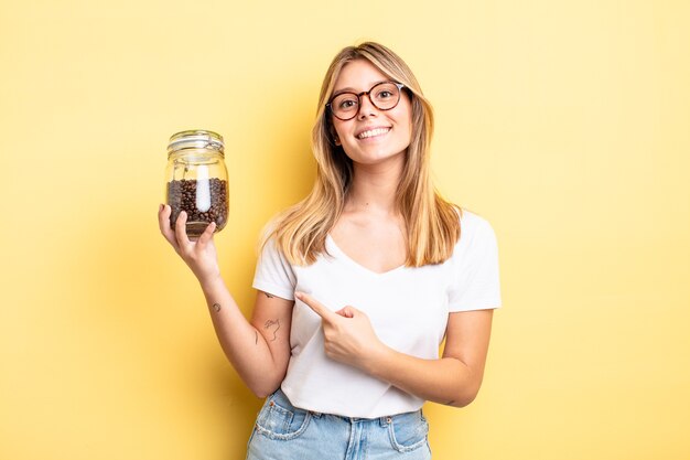 Bella ragazza bionda che sorride allegramente, si sente felice e indica il lato. concetto di chicchi di caffè