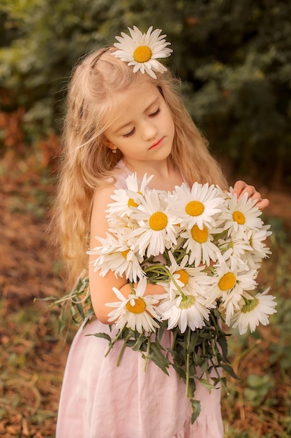 bella ragazza bionda con i capelli lunghi con margherite bianche nelle sue mani