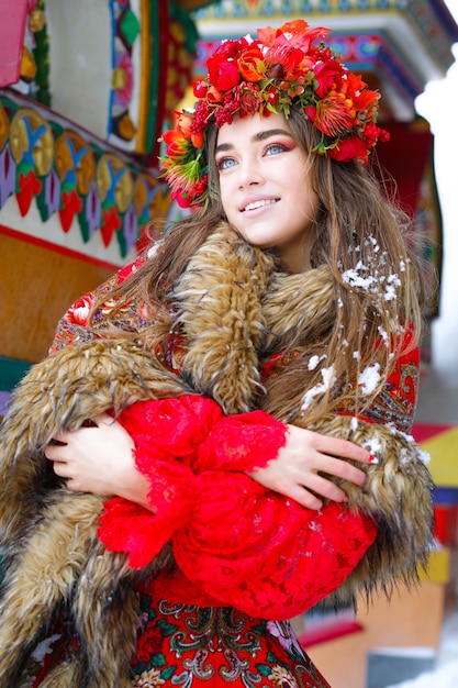 Bella ragazza bionda dai capelli lunghi in abiti nazionali tradizionali russi in inverno