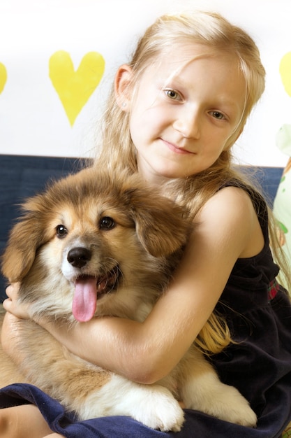 Bella ragazza bionda e cucciolo lanuginoso di corgi che esaminano la macchina fotografica