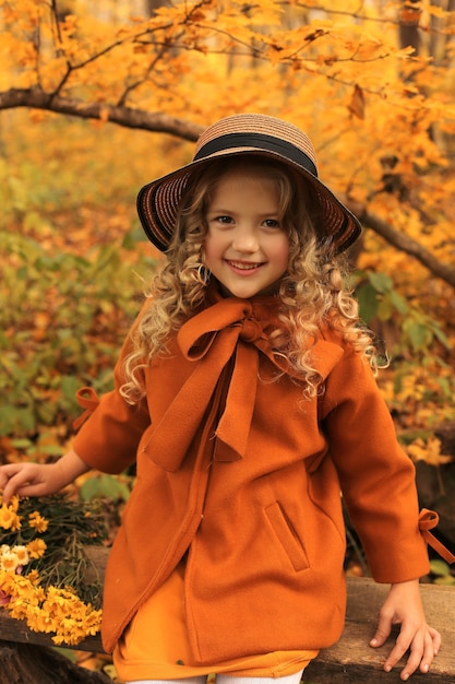 bella ragazza bionda felice in un cappotto beige in un cappello nel parco della città autunno