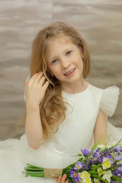 bella ragazza bionda felice in un vestito bianco con i fiori nelle sue mani