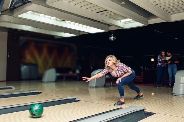 Bella ragazza bionda gioca a bowling nel club