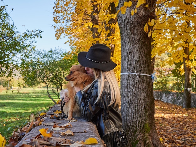 Bella ragazza bionda gioca con il cane di Pomerania