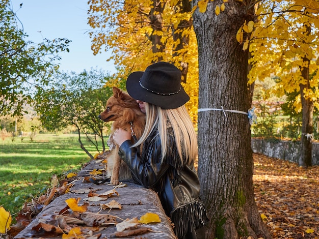 Bella ragazza bionda gioca con il cane di Pomerania