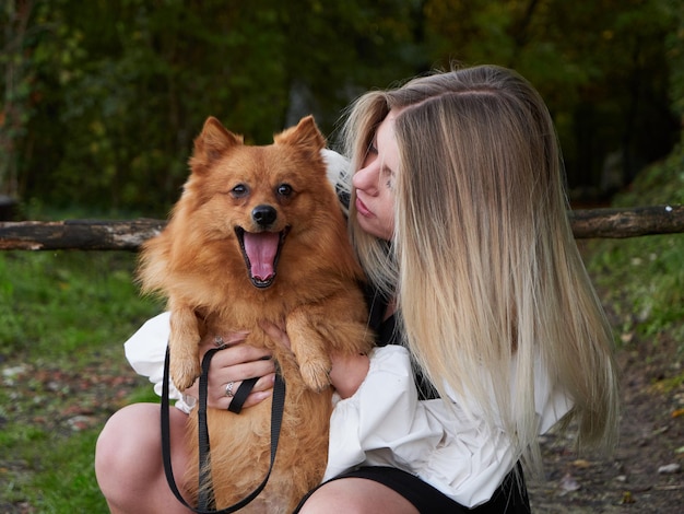 Bella ragazza bionda gioca con il cane di Pomerania