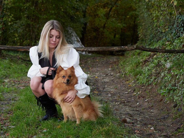 Bella ragazza bionda gioca con il cane di Pomerania