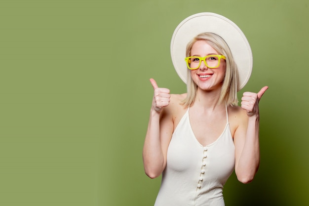 Bella ragazza bionda in occhiali e cappello bianco