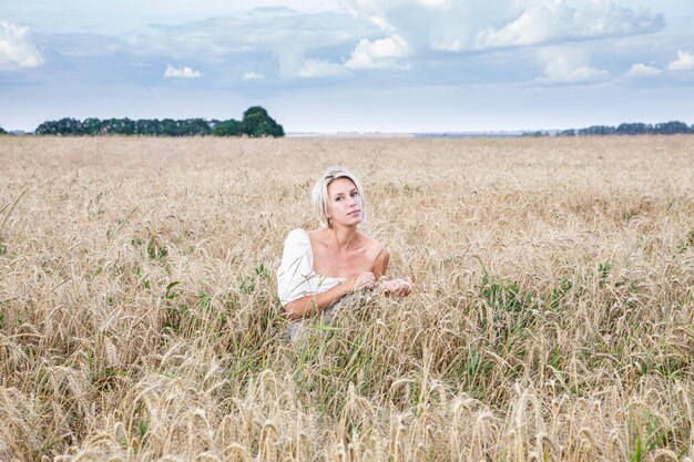 Bella ragazza bionda in un campo di grano