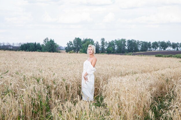 Bella ragazza bionda in un campo di grano