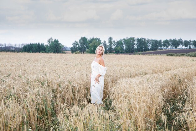 Bella ragazza bionda in un campo di grano