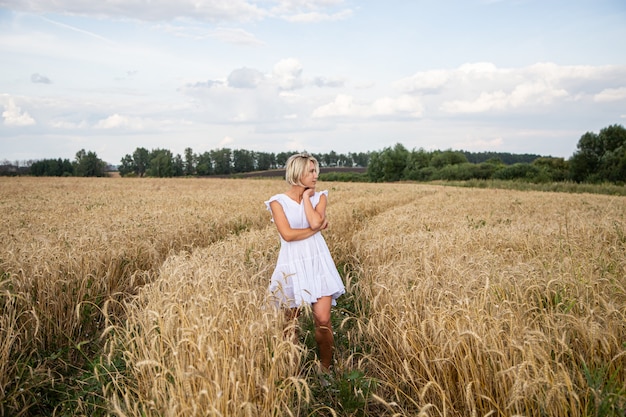 Bella ragazza bionda in un campo di grano