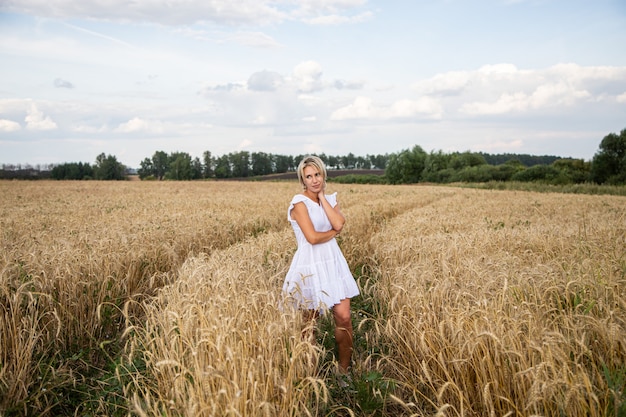 Bella ragazza bionda in un campo di grano