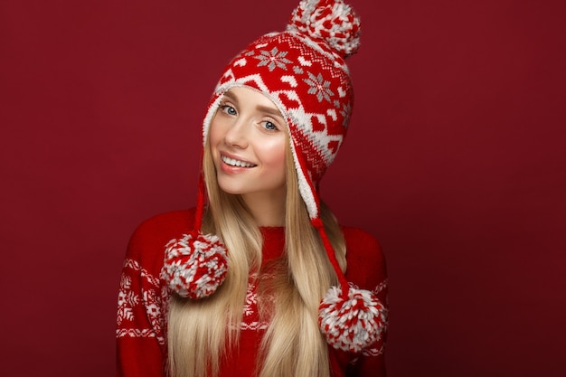 Bella ragazza bionda nell'immagine di un nuovo anno con cappello e maglione caldi. Fronte di bellezza con trucco festivo. Foto scattata in studio