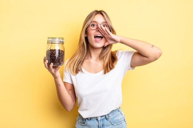 Bella ragazza bionda sentirsi felice, dando un grande grido con le mani vicino alla bocca. concetto di chicchi di caffè