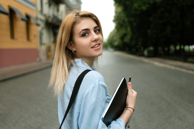 Bella ragazza bionda studentessa che cammina per la città