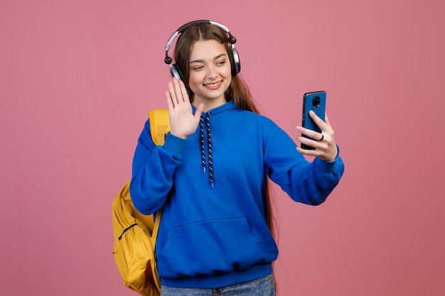 Bella ragazza bruna con auricolari in piedi prendendo selfie