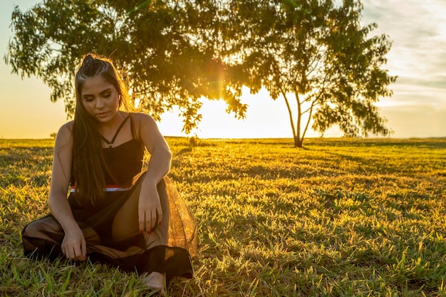 Bella ragazza bruna in posa sulle foto in natura al tramonto