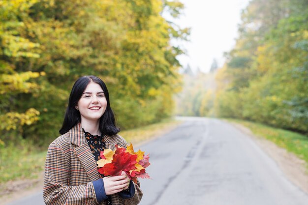 Bella ragazza bruna nel parco d'autunno