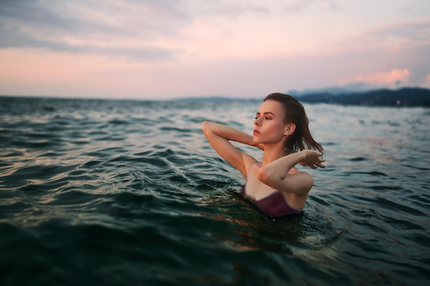 Bella ragazza bruna sta nuotando nell'acqua