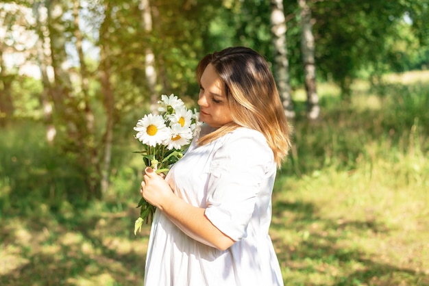 Bella ragazza cammina nella foresta con le margherite