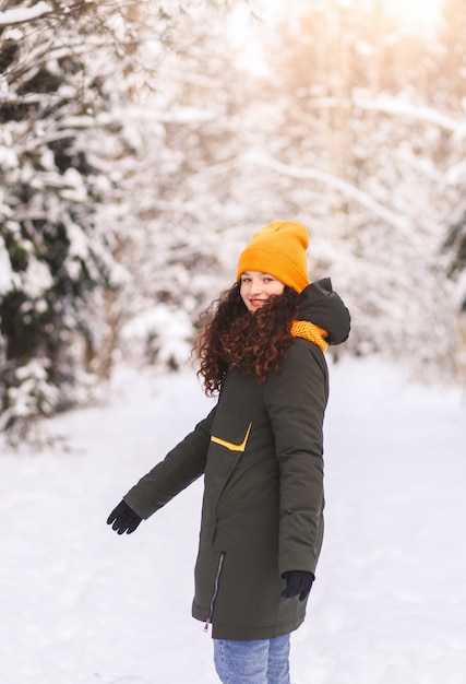 Bella ragazza cammina nella foresta invernale in una giornata di sole