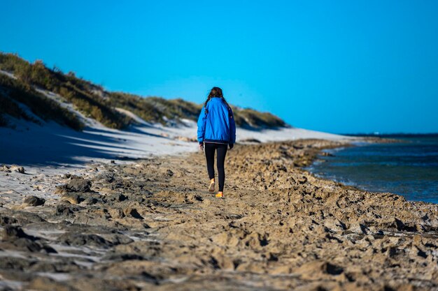 bella ragazza cammina sulla spiaggia della baia di corallo che si affaccia sulla barriera corallina di ningaloo al mattino