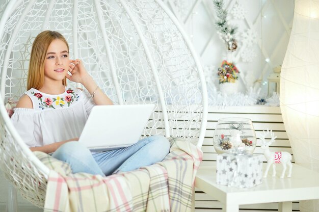 Bella ragazza carina che utilizza il computer portatile a casa