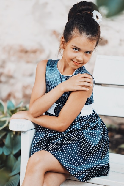 Bella ragazza castana in un vestito blu a pois in estate nel parco. Bambino alla moda in natura. Foto di alta qualità