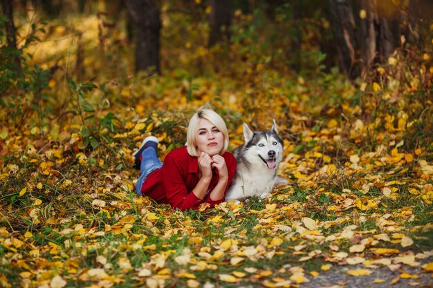 Bella ragazza caucasica gioca con il cane husky nella foresta di autunno