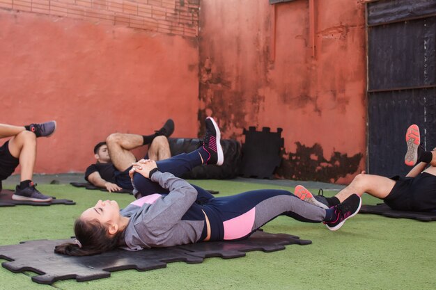 Bella ragazza che allunga le gambe con i suoi compagni di allenamento nel cortile della palestra.