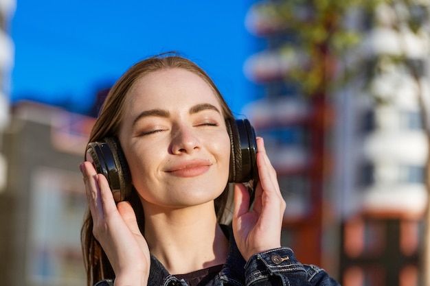 Bella ragazza che ascolta la musica sulle cuffie street style all'aperto