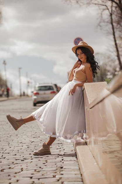 bella ragazza che cammina per la città con una gonna e un cappello bianchi