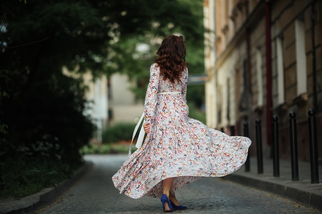 Bella ragazza che cammina sulla strada in primavera. Giovane donna che gode del tempo del tempo di primavera.