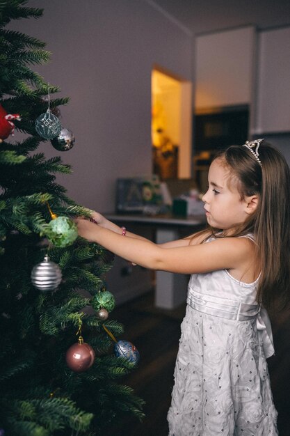 Bella ragazza che decora l'albero di Natale con le palle