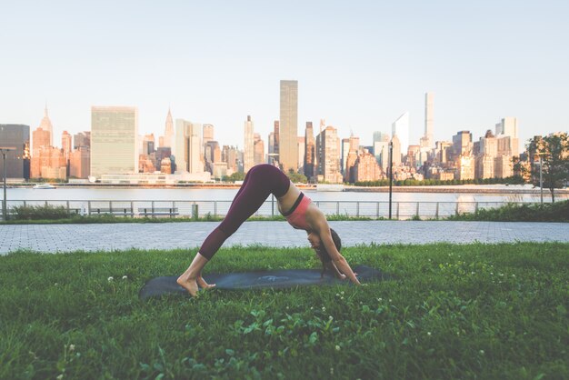 Bella ragazza che fa addestramento di yoga di mattina a New York