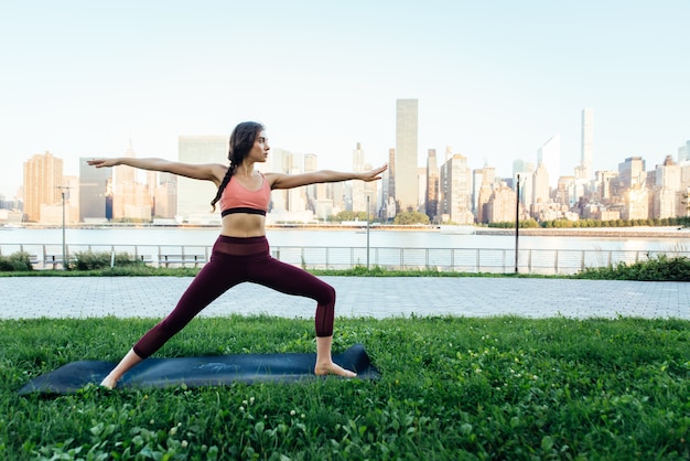 Bella ragazza che fa addestramento di yoga di mattina a New York