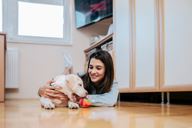 Bella ragazza che gioca con il cucciolo carino a casa.