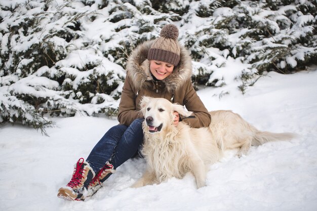 Bella ragazza che gioca con il suo cane nella neve. Golden retriever