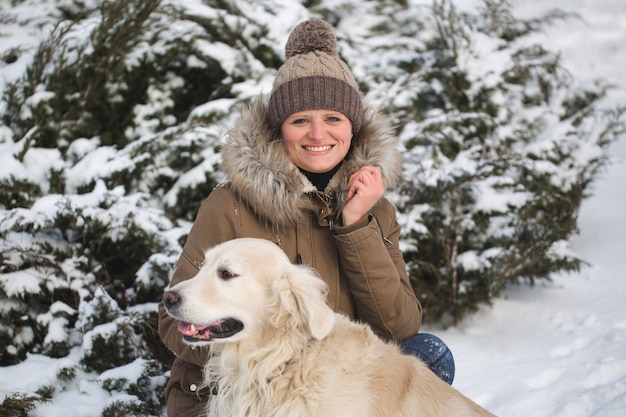 Bella ragazza che gioca con il suo cane nella neve. Golden retriever