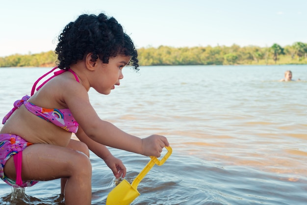 Bella ragazza che gioca sulla spiaggia in una giornata di sole