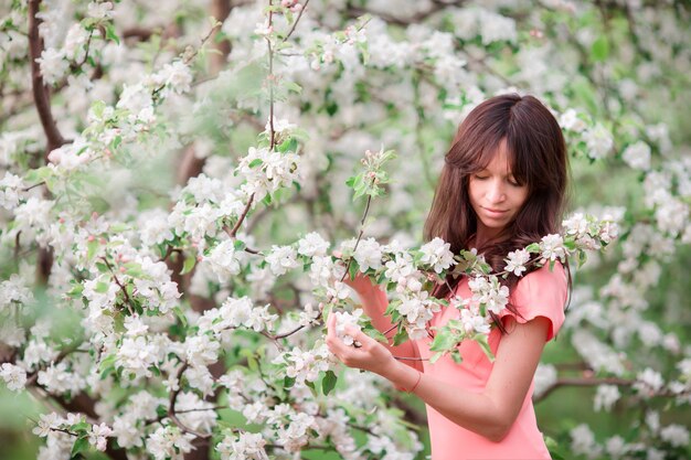 Bella ragazza che gode dell'odore nel giardino della ciliegia di primavera